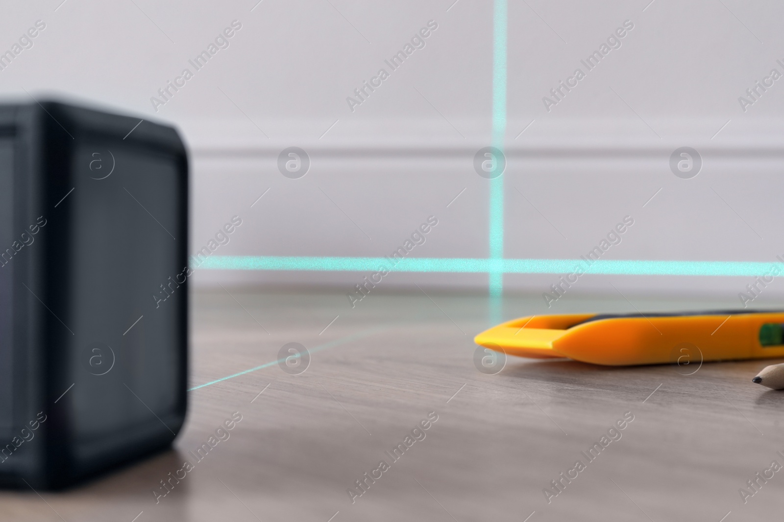 Photo of Cross line laser level and other tools on wooden floor indoors