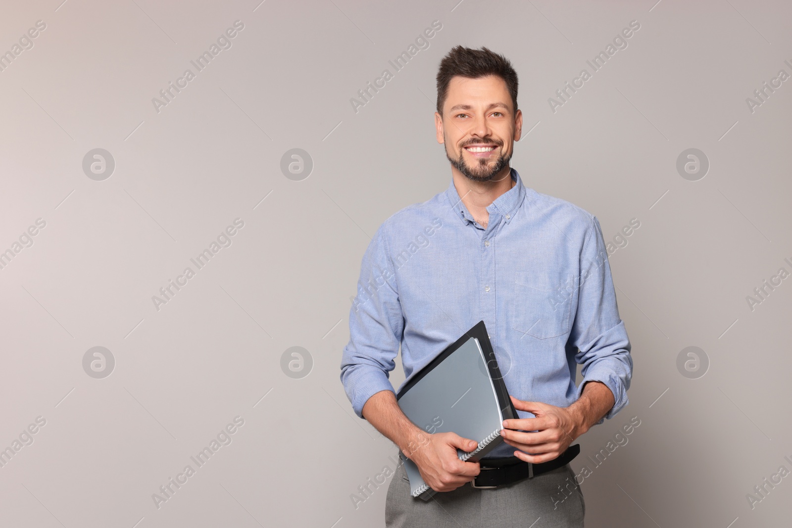 Photo of Happy teacher with stationery against beige background. Space for text