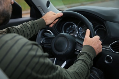 Photo of Man holding steering wheel in car, closeup. Driving license test