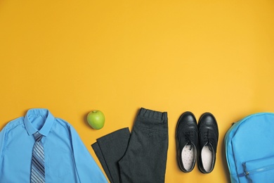 Flat lay composition with school uniform on yellow background. Space for text