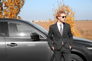 Young businessman near modern car on sunny day, outdoors