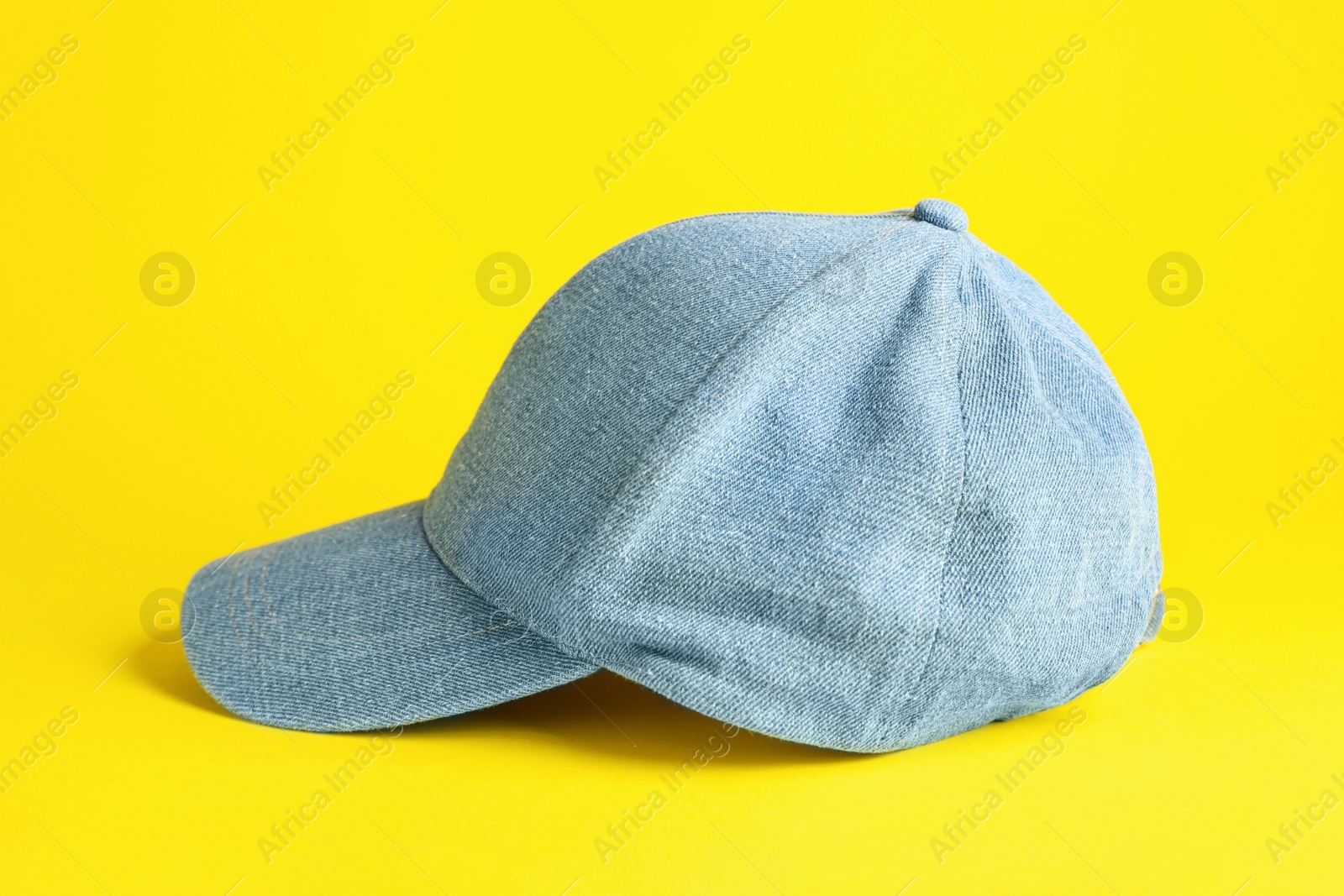 Photo of Stylish light blue denim baseball cap on yellow background