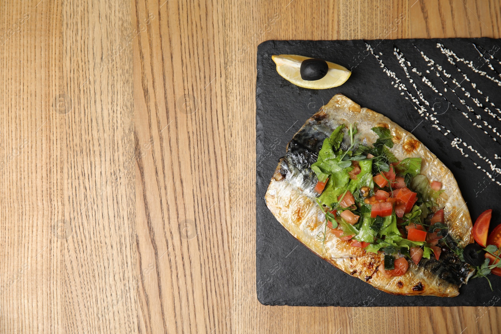 Photo of Delicious grilled fish served on wooden table, top view. Space for text