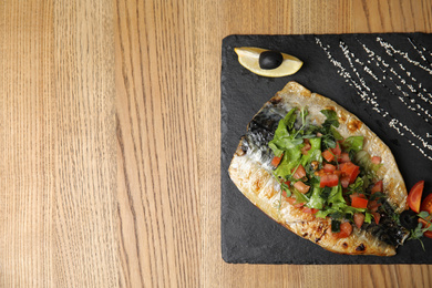 Photo of Delicious grilled fish served on wooden table, top view. Space for text