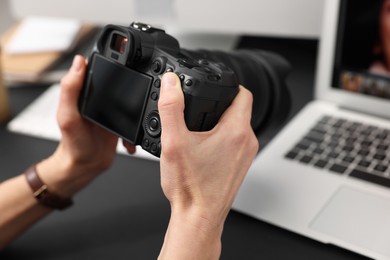 Photo of Professional photographer with digital camera at table indoors, closeup