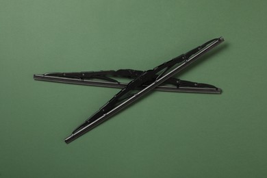 Car windshield wipers on dark green background, flat lay