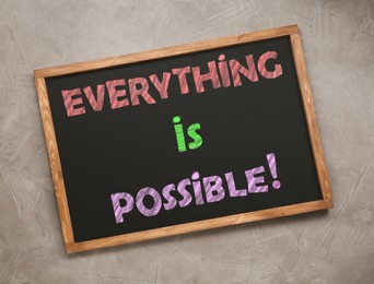 Image of Small chalkboard with motivational quote Everything is possible on grey background, top view