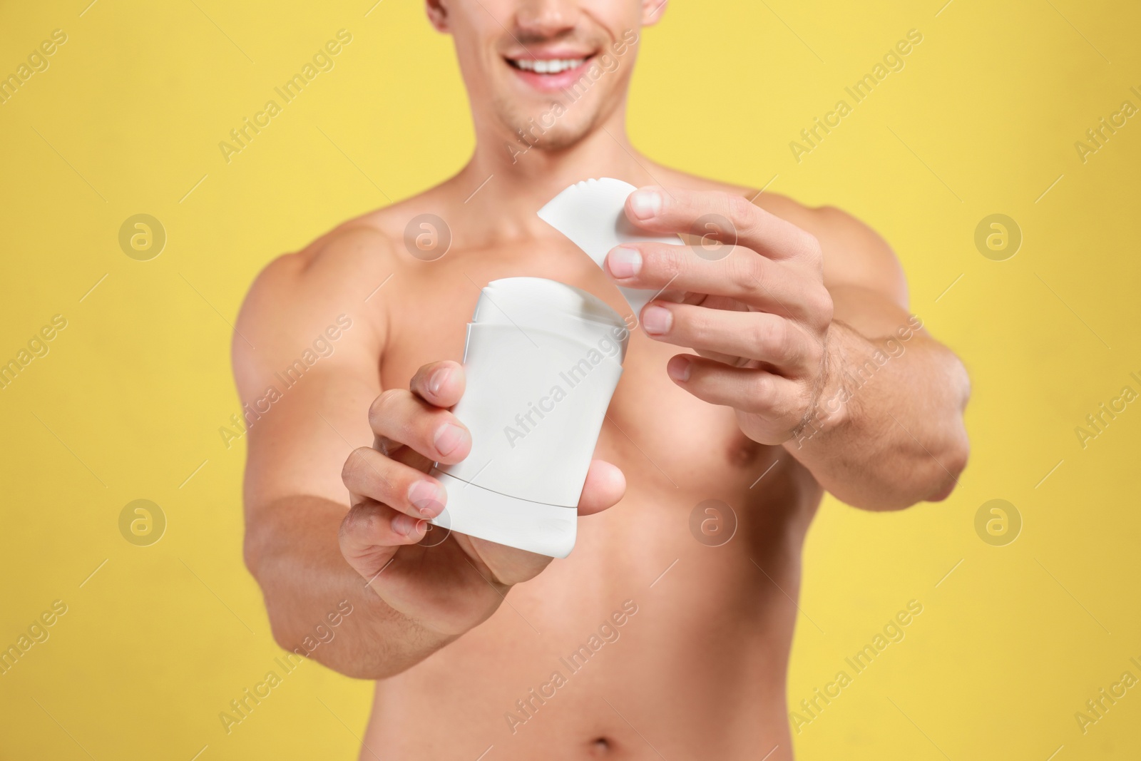 Photo of Young man with deodorant on yellow background, closeup