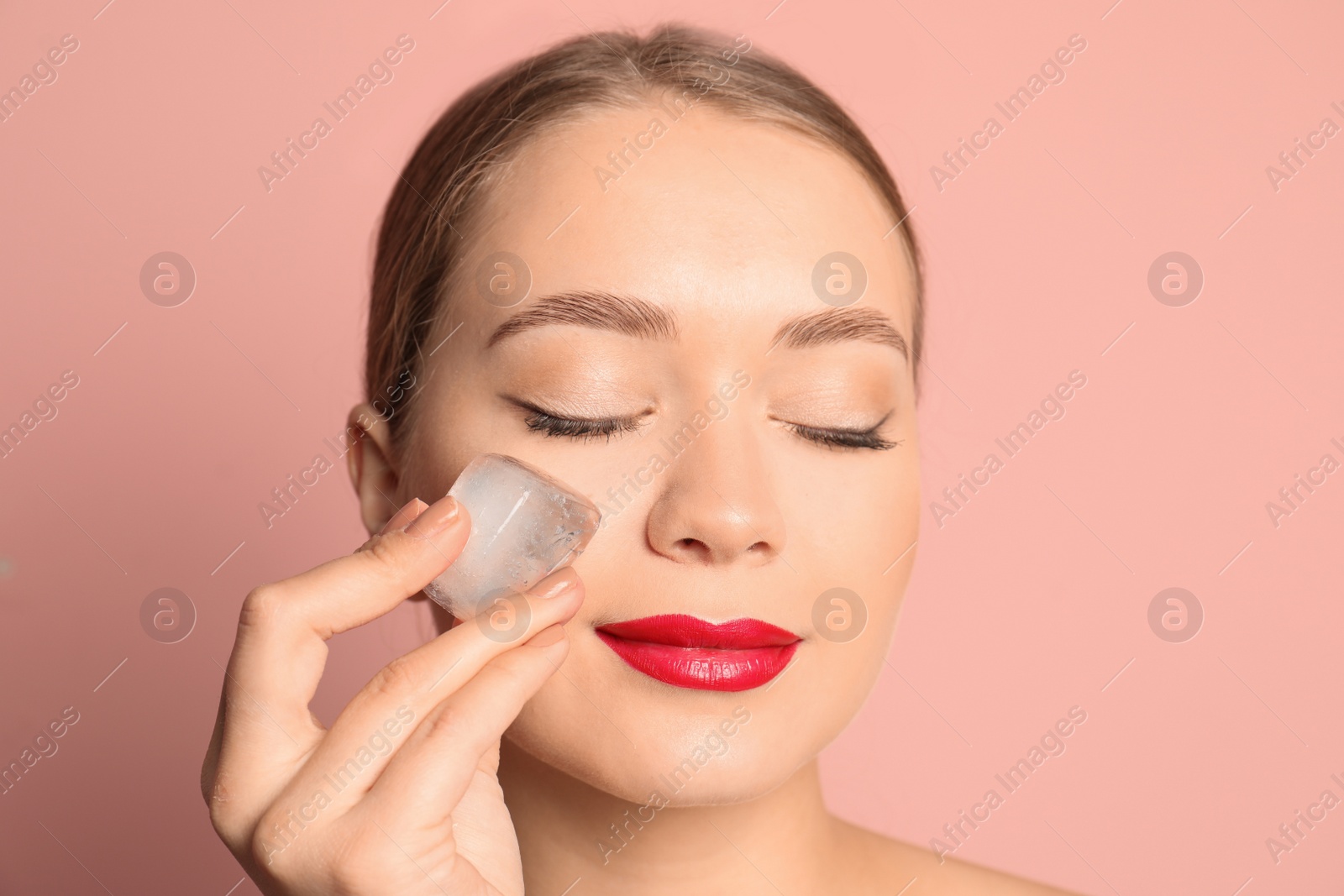 Photo of Young woman with ice cube on color background. Skin care