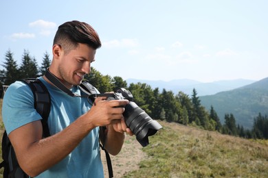 Photo of Professional photographer with modern camera in mountains. Space for text