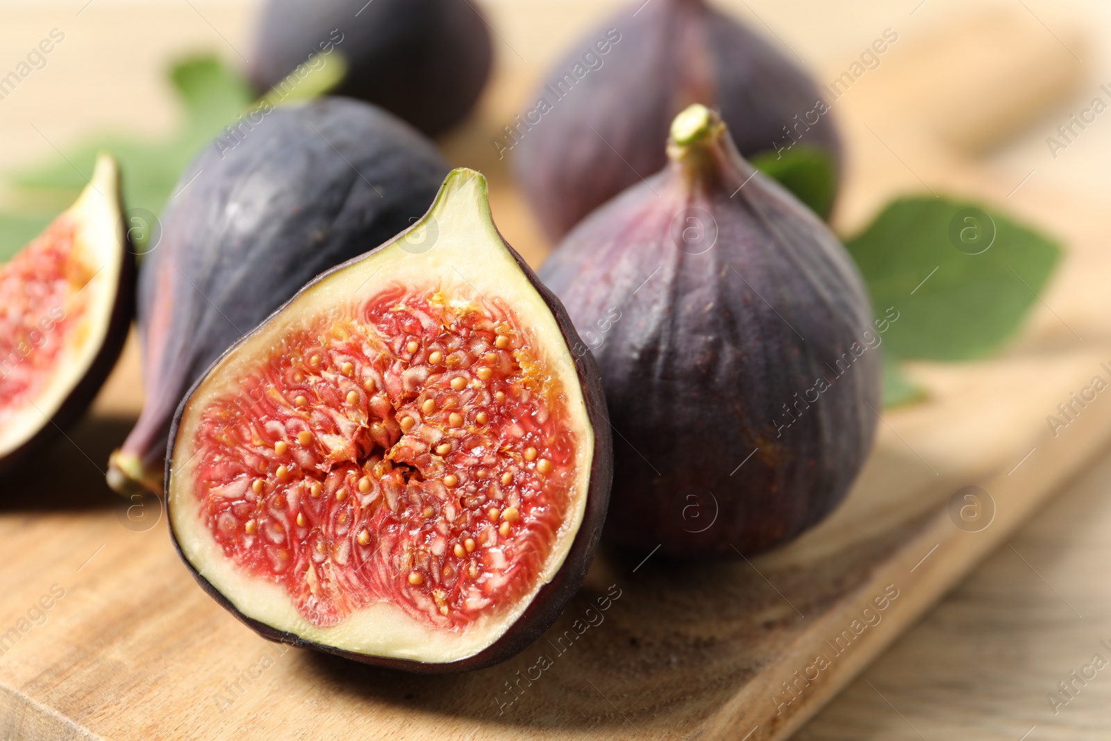 Photo of Whole and cut ripe figs on wooden table, closeup