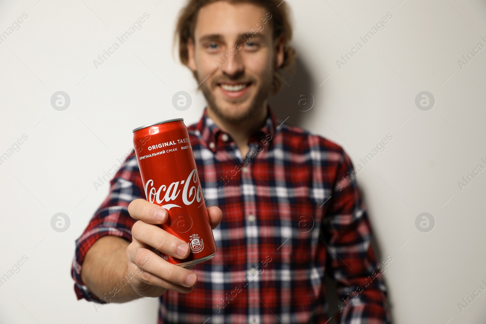 Photo of MYKOLAIV, UKRAINE - NOVEMBER 28, 2018: Young man with Coca-Cola can on white background