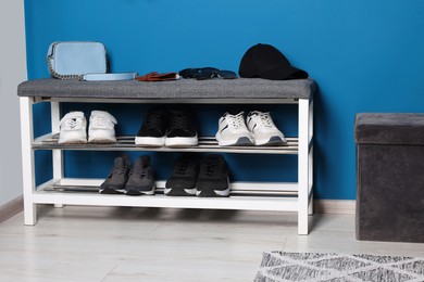 Photo of Stylish hallway with shoe storage bench and ottoman near blue wall. Interior design