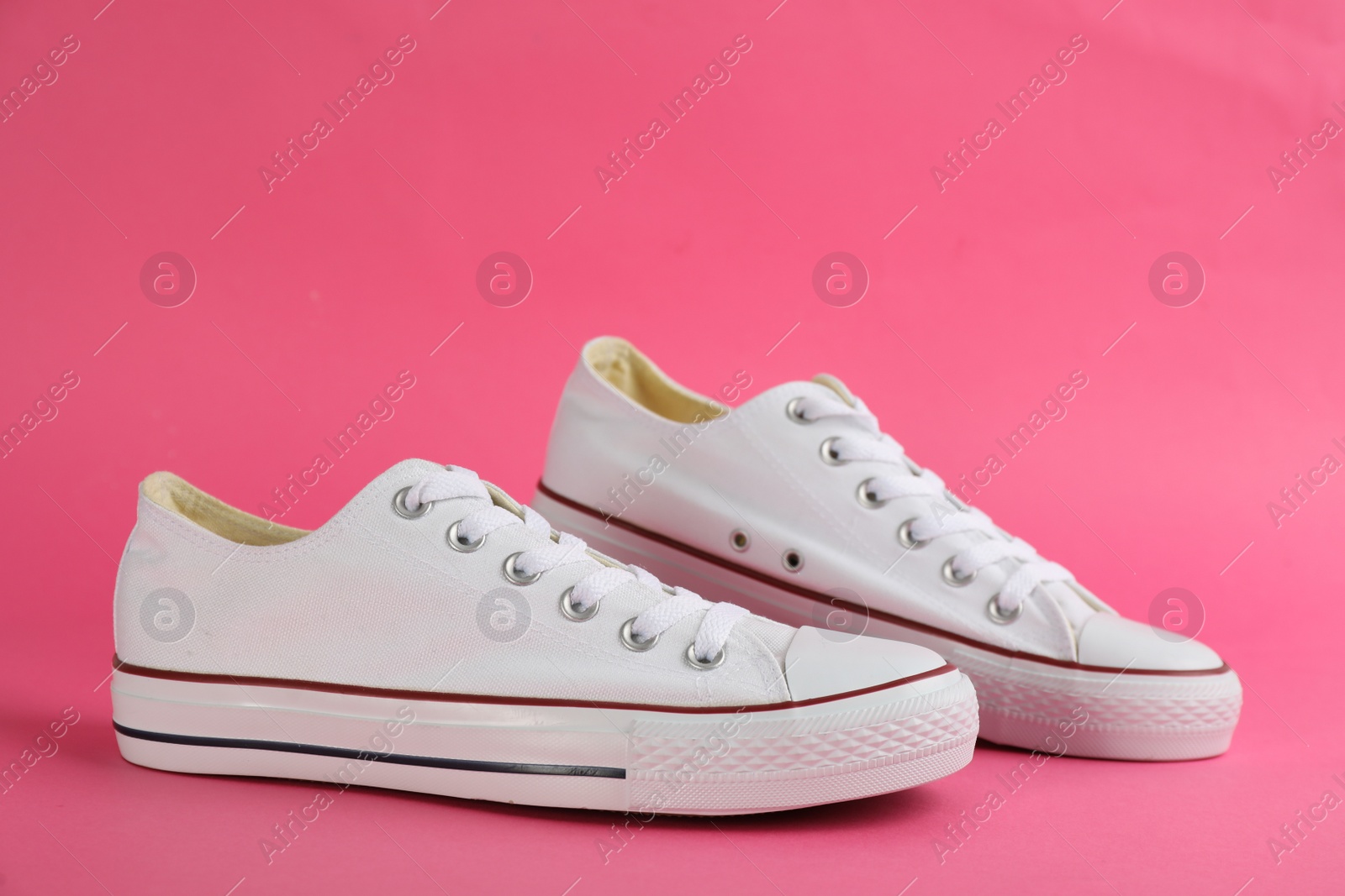 Photo of Pair of stylish sneakers on pink background