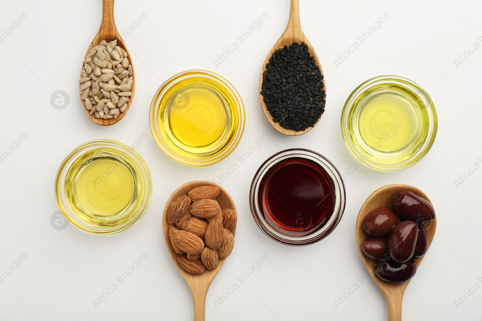 Photo of Vegetable fats. Different cooking oils in bowls and spoons with ingredients on white background, flat lay