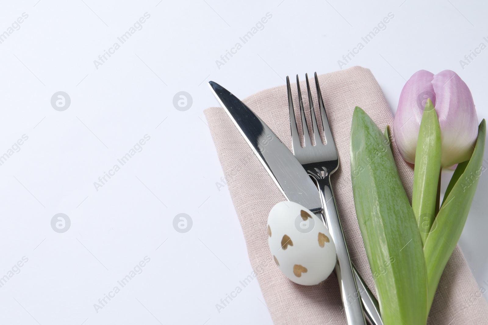 Photo of Cutlery set, Easter egg and tulip on white background, space for text. Festive table setting