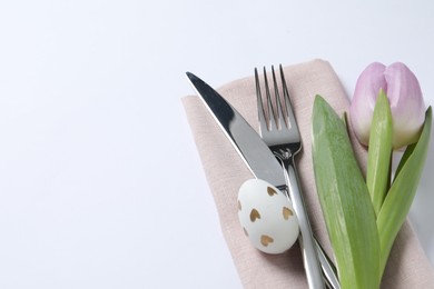 Photo of Cutlery set, Easter egg and tulip on white background, space for text. Festive table setting