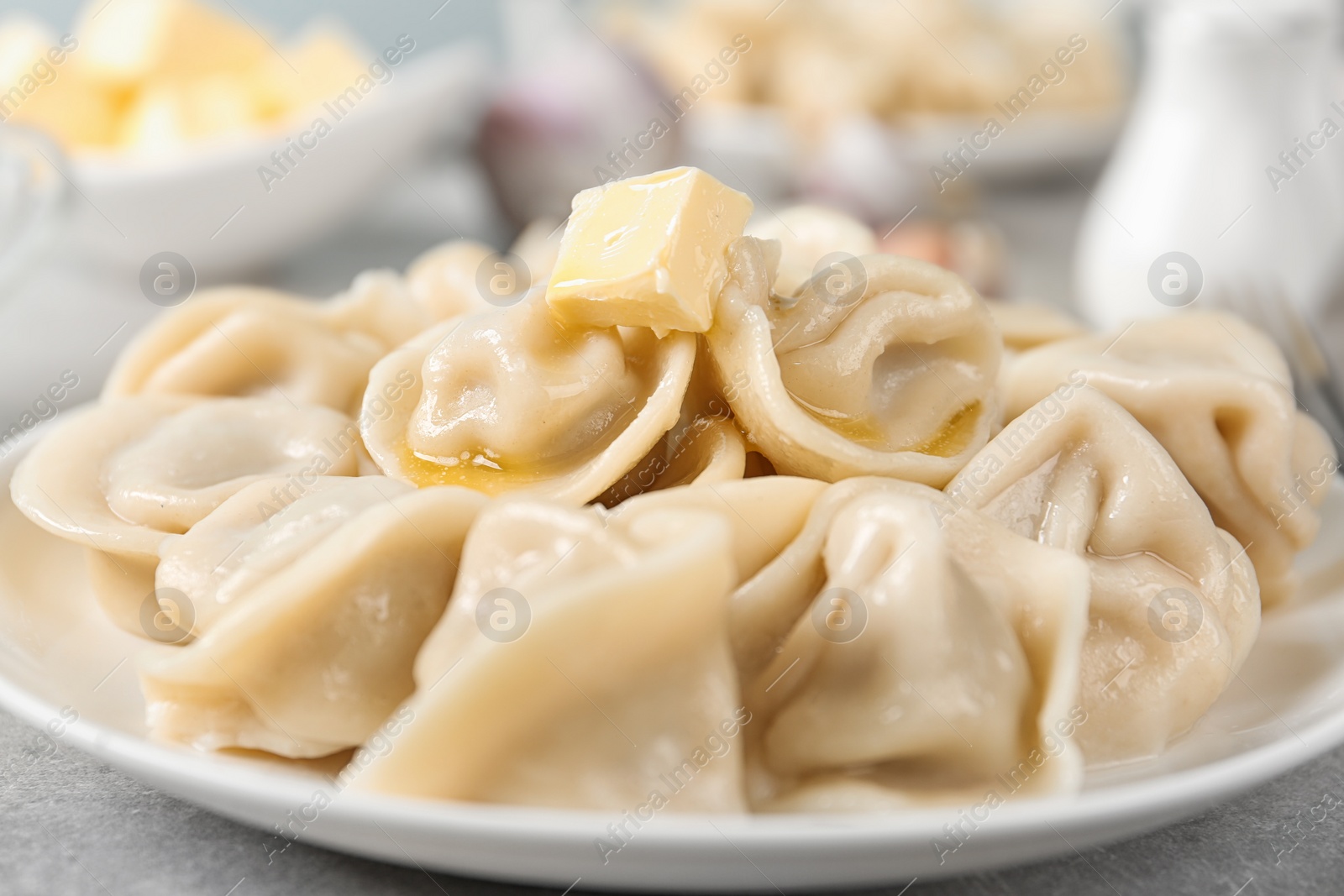 Photo of Tasty dumplings with butter on light grey table, closeup