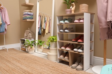 Photo of Stylish dressing room interior with shoes in storage unit