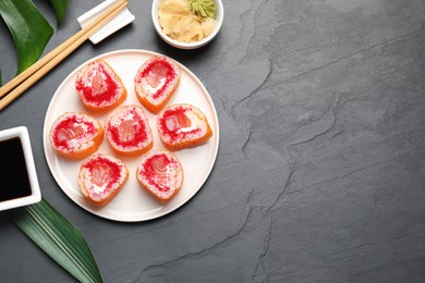 Photo of Flat lay composition with sushi rolls on black textured table. Space for text