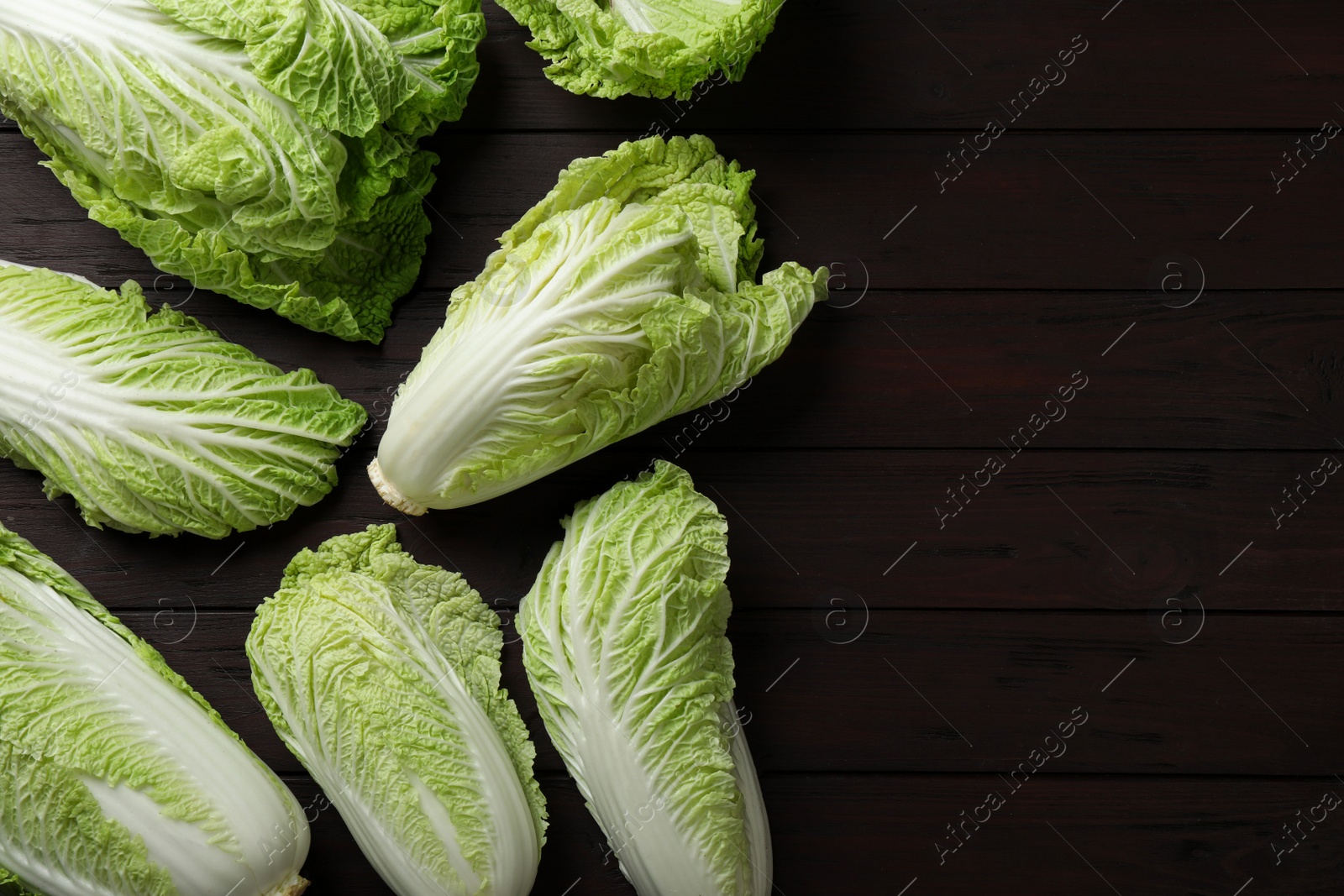 Photo of Fresh ripe Chinese cabbages on dark wooden table, fat lay. Space for text