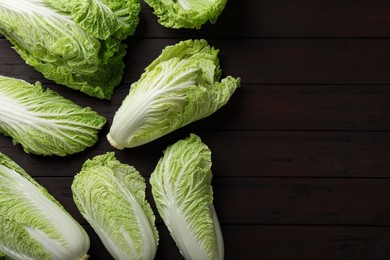 Photo of Fresh ripe Chinese cabbages on dark wooden table, fat lay. Space for text