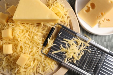 Photo of Grated, whole pieces of cheese and grater on table, top view