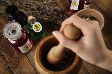 Photo of Woman preparing poison at wooden table, closeup