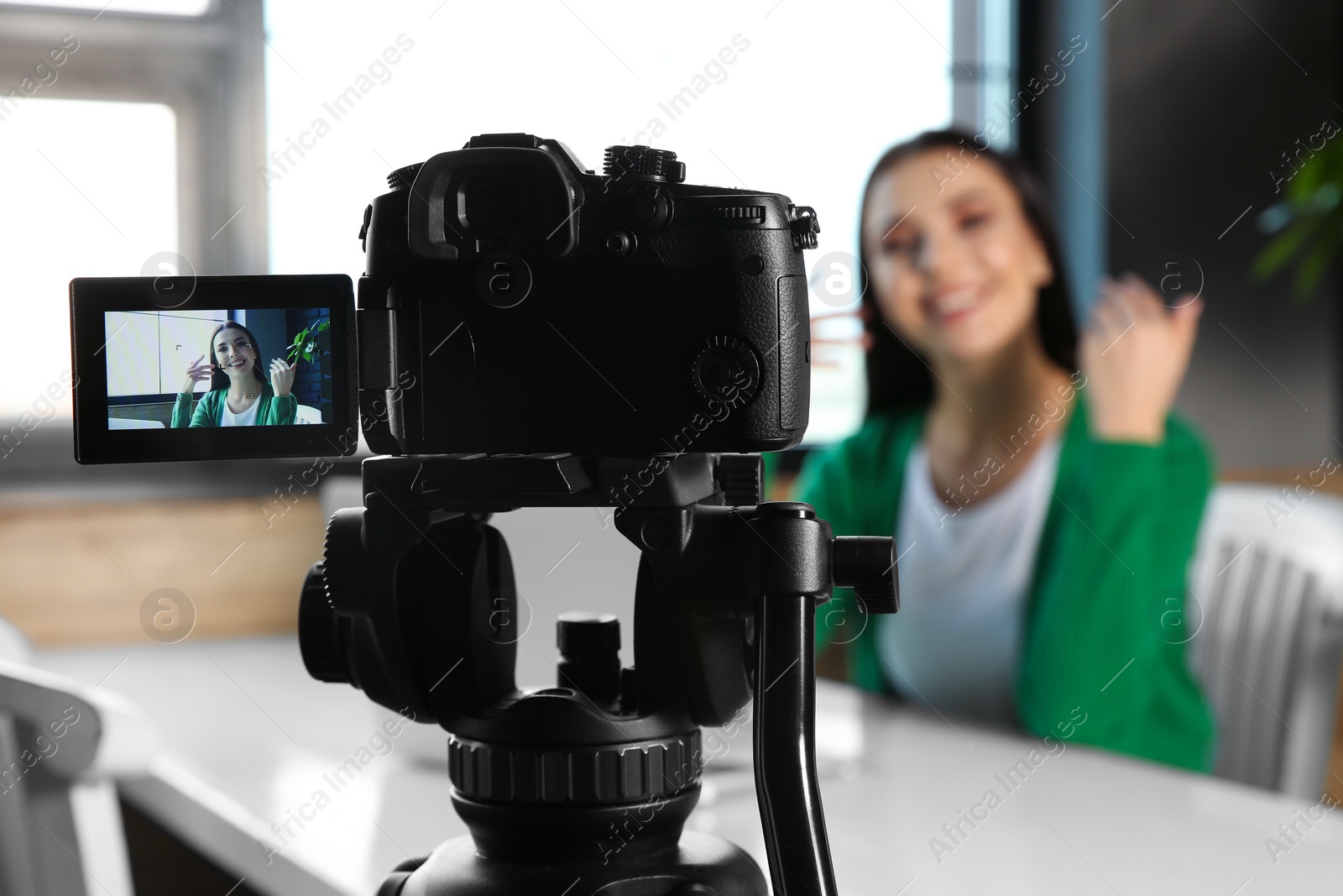 Photo of Young blogger recording video at cafe, focus on camera screen