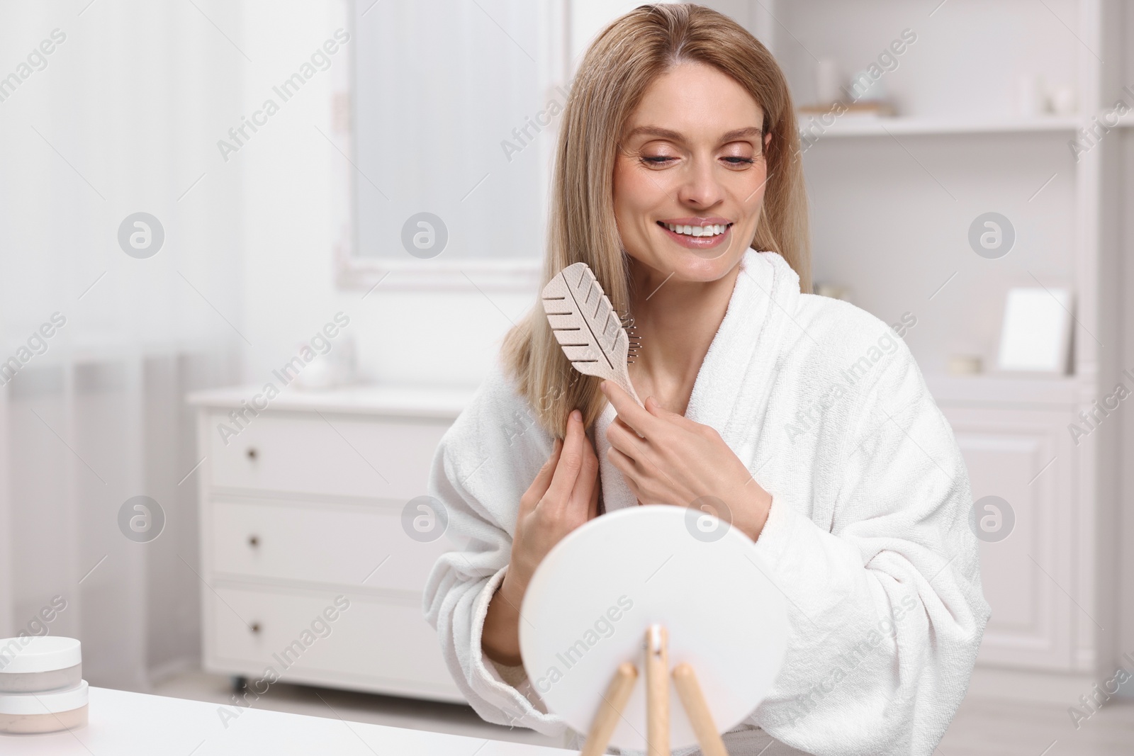 Photo of Beautiful woman brushing her hair in room