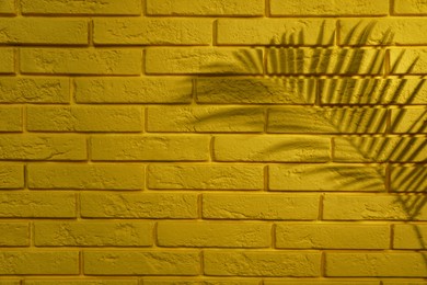 Photo of Shadow of tropical palm leaf on yellow brick wall, space for text