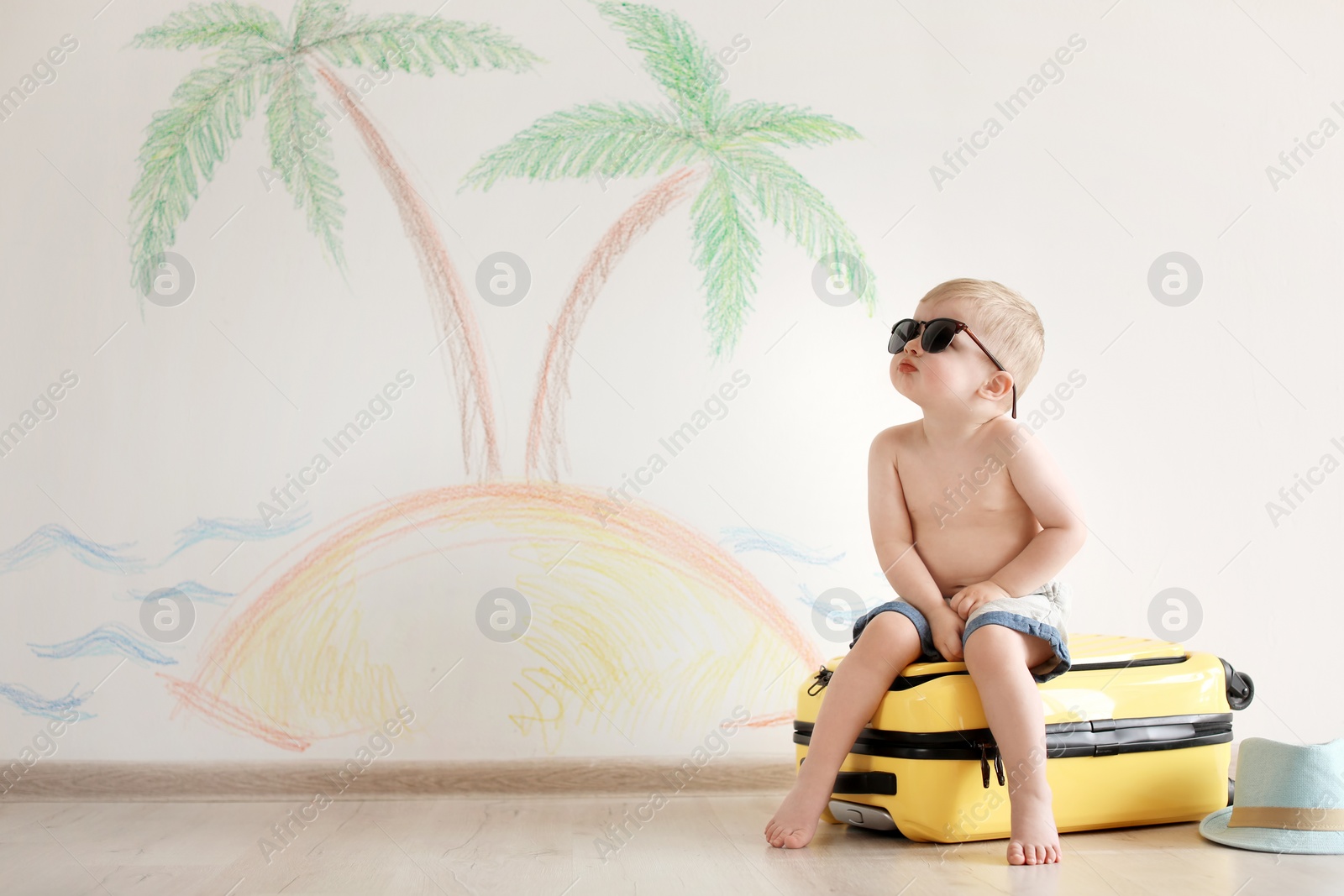 Photo of Adorable little child playing traveler with suitcase indoors