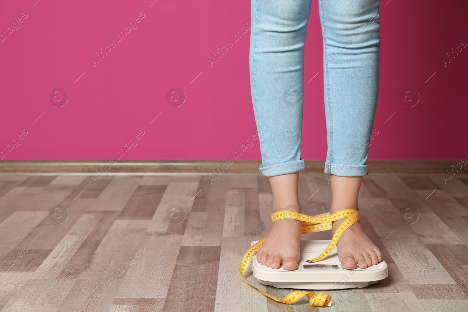 Photo of Woman with tied legs measuring her weight using scales on floor. Healthy diet