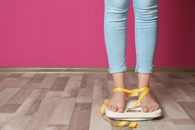 Photo of Woman with tied legs measuring her weight using scales on floor. Healthy diet