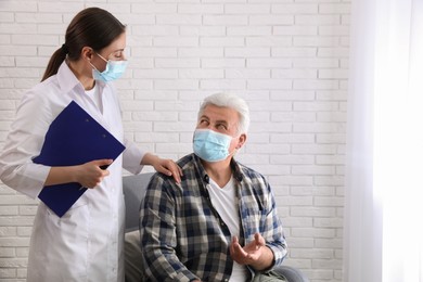 Doctor taking care of senior woman in protective mask at nursing home