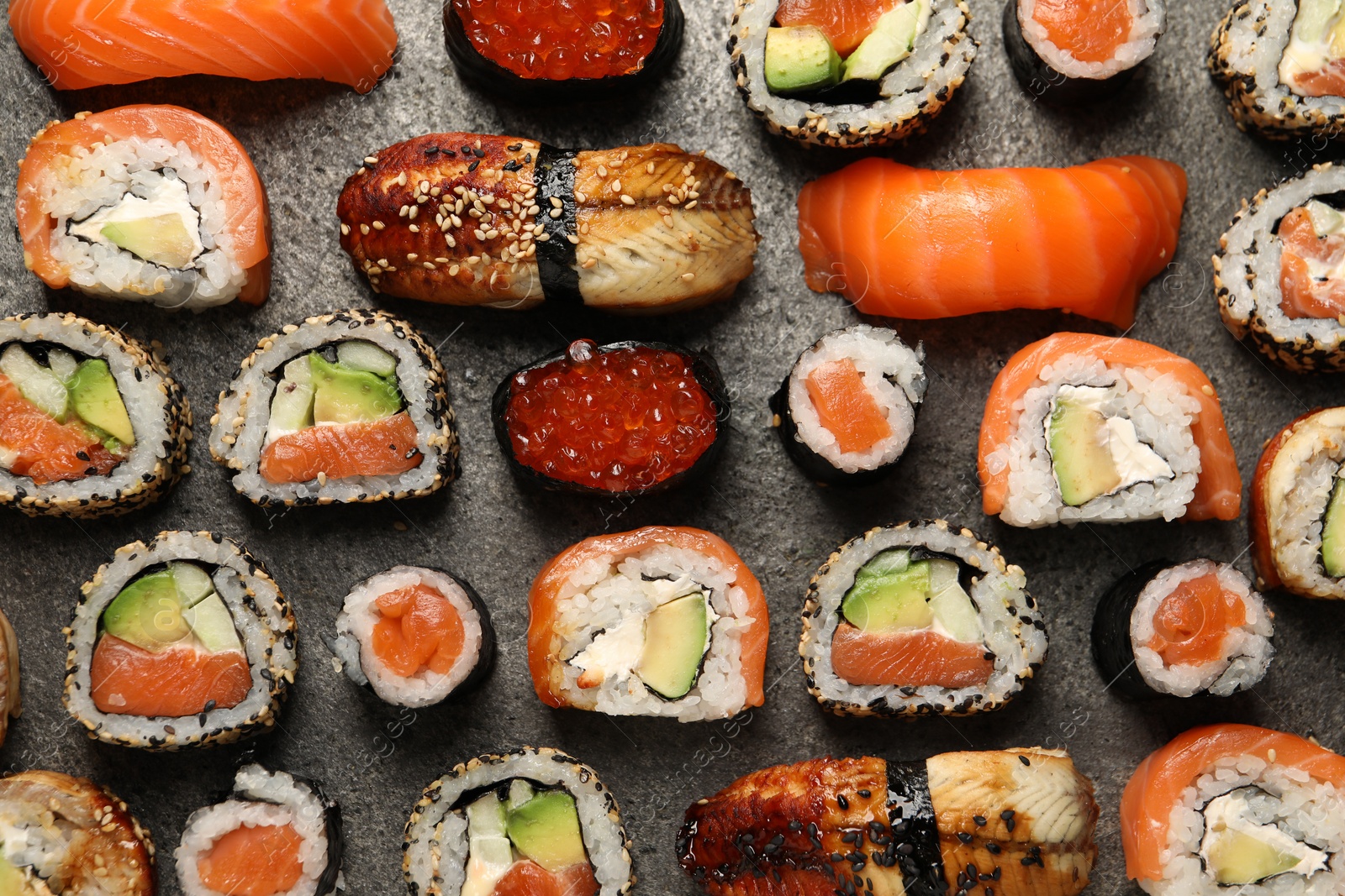 Photo of Different tasty sushi rolls on grey table, flat lay