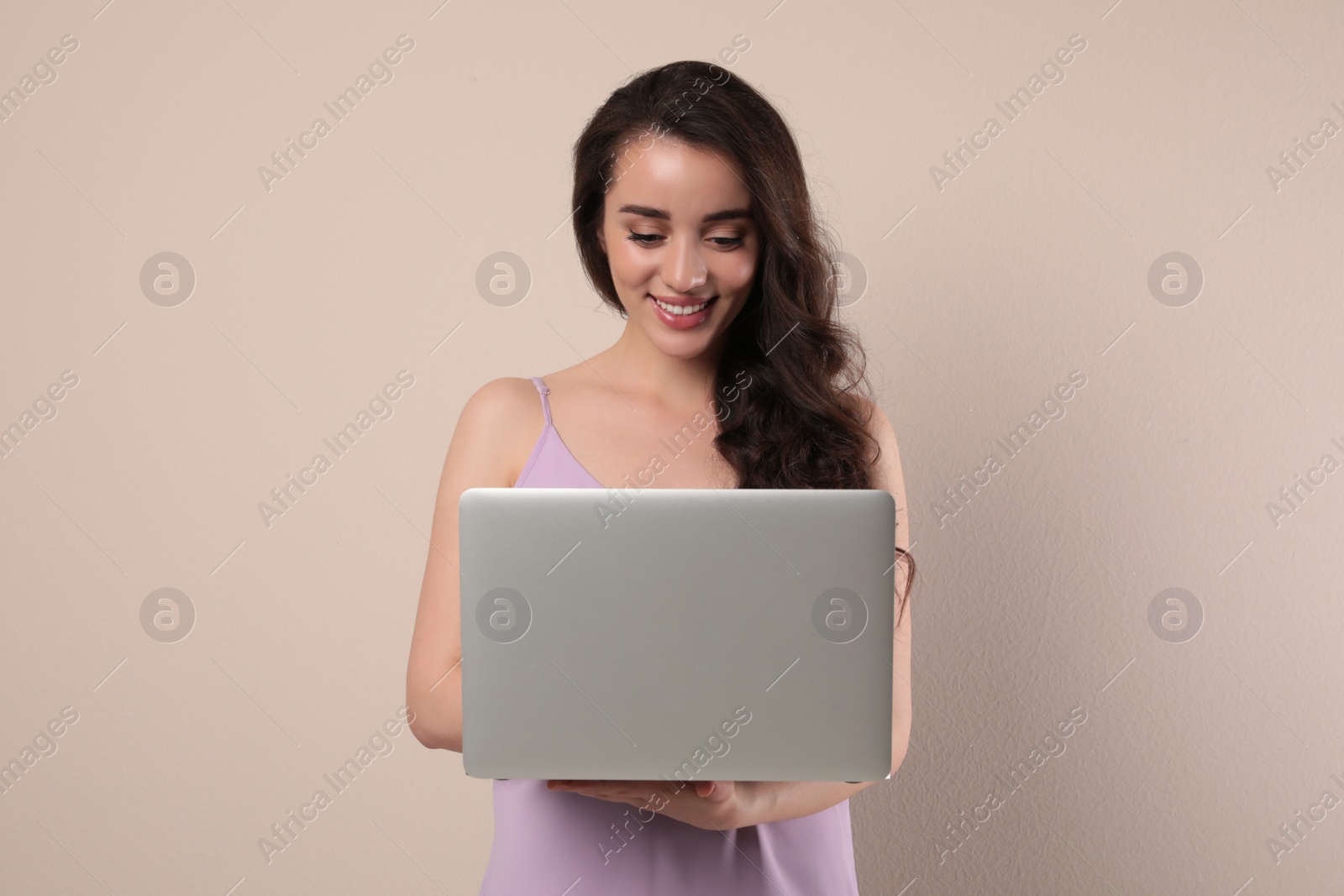 Photo of Young woman with laptop on beige background