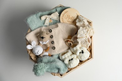Photo of Box with baby clothes, shoes and accessories on light background, top view