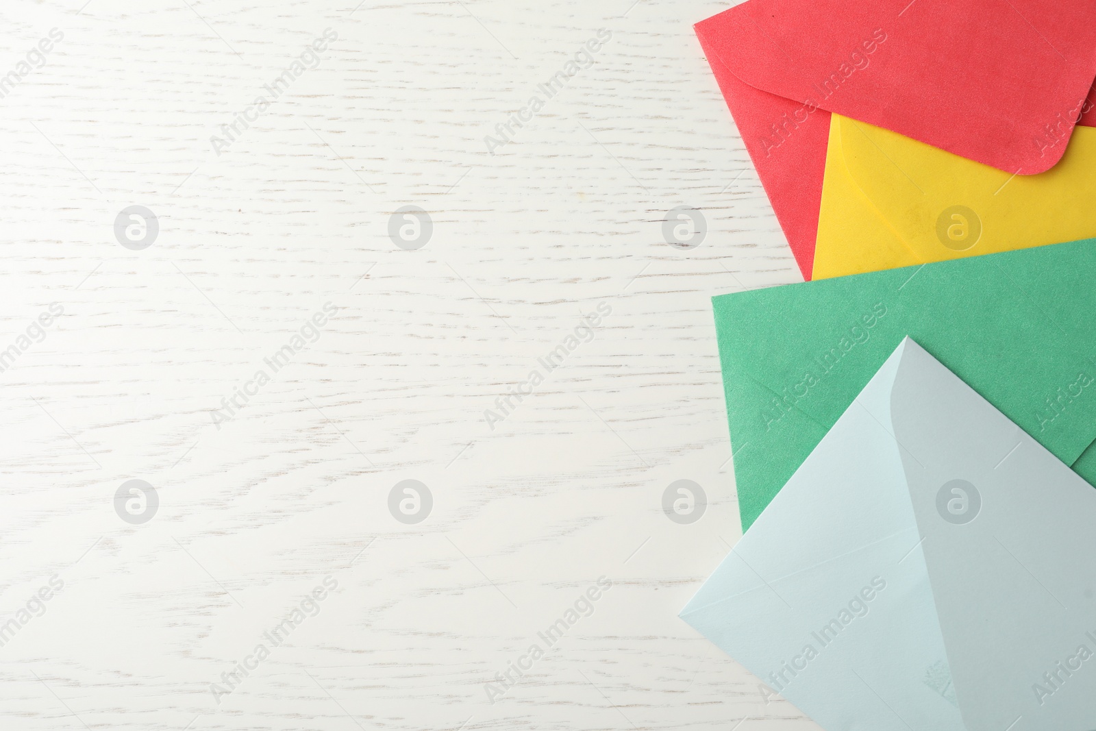 Photo of Colorful paper envelopes on white wooden background, flat lay. Space for text