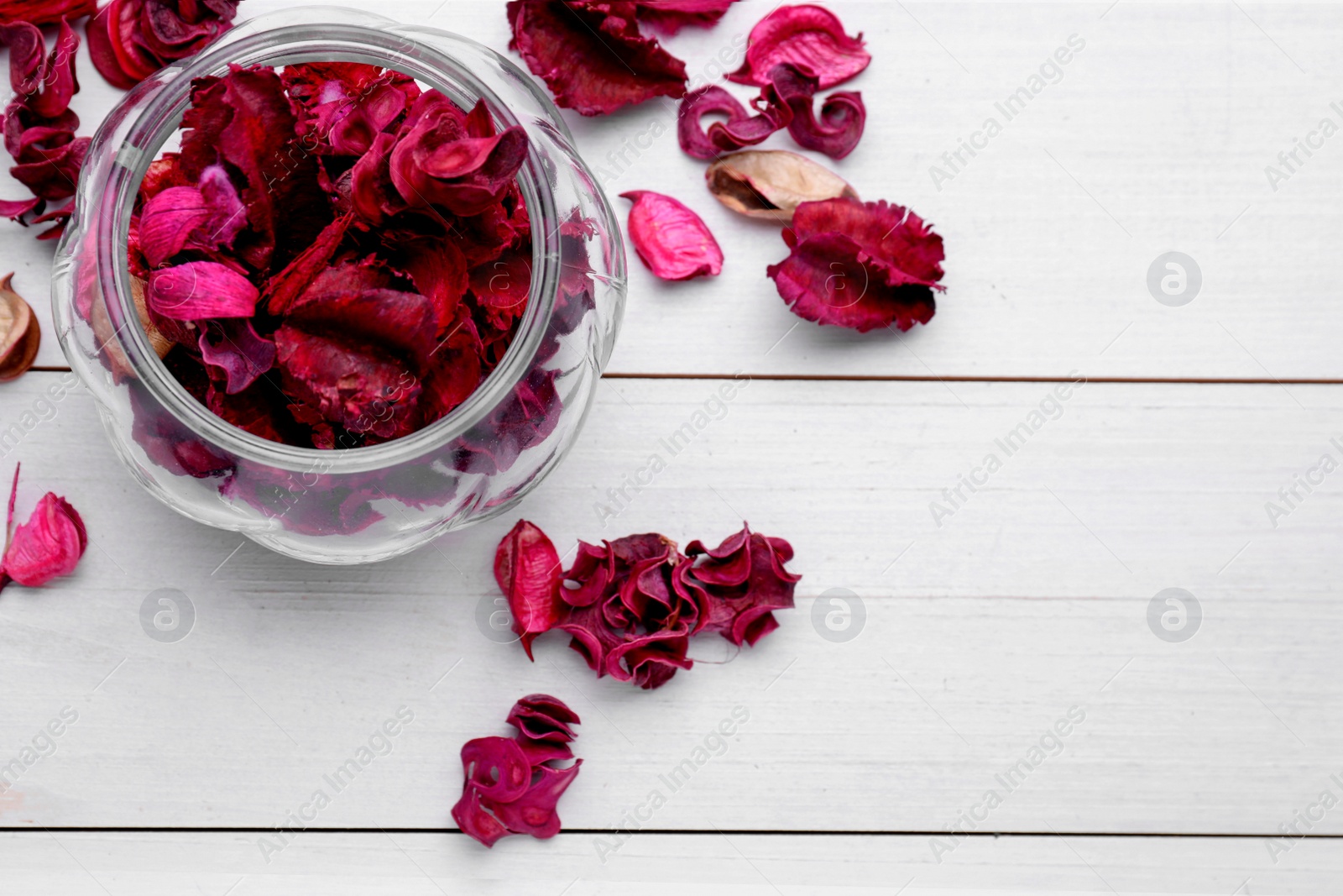 Photo of Aromatic potpourri of dried flowers in glass jar on white wooden table, flat lay. Space for text