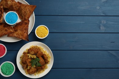 Photo of Traditional Indian food and color powders on blue wooden table, flat lay with space for text. Holi festival celebration