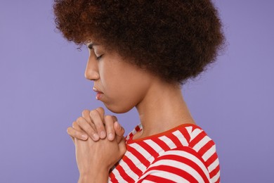 Photo of Woman with clasped hands praying to God on purple background