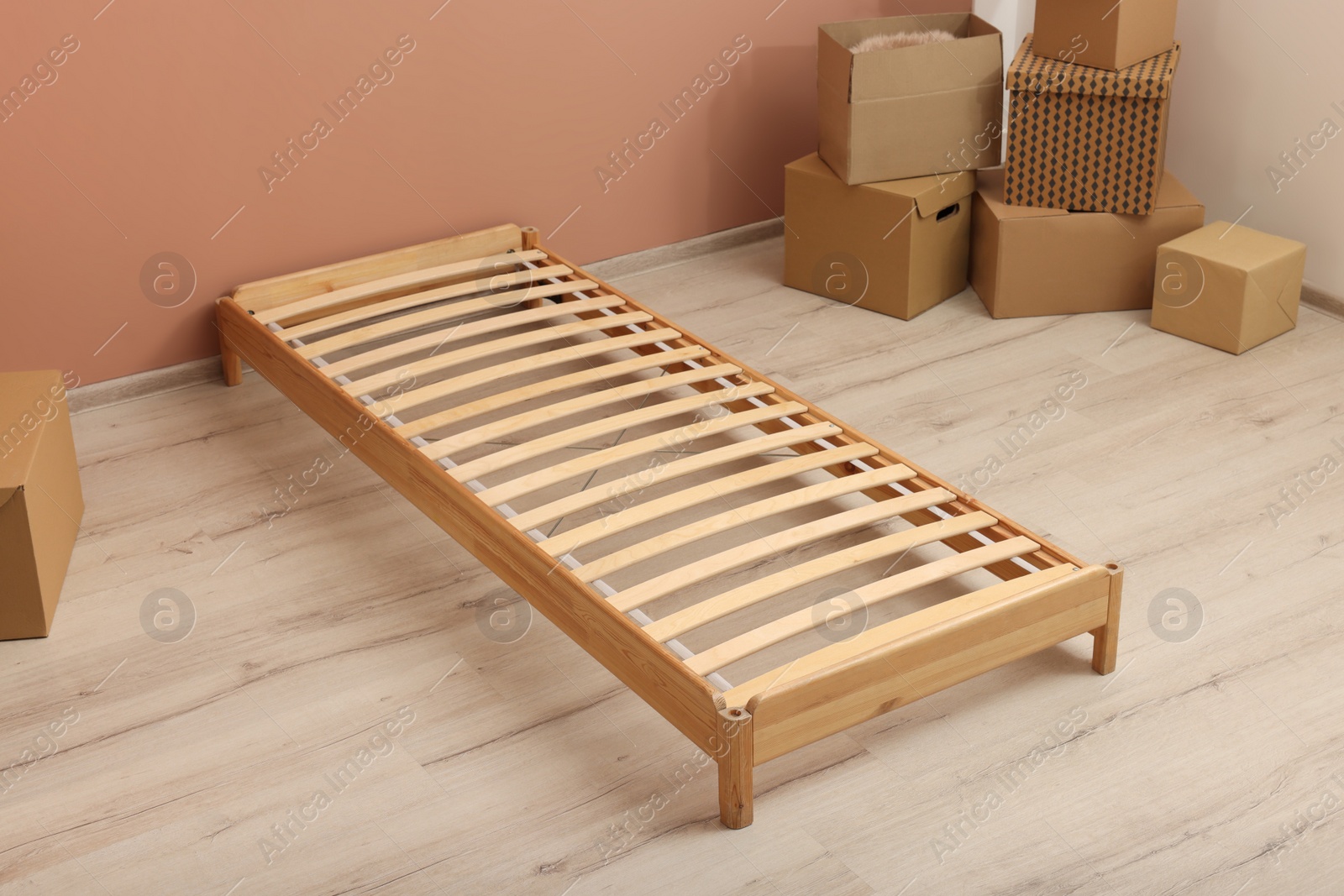 Photo of Wooden bed frame and cardboard boxes on floor in room