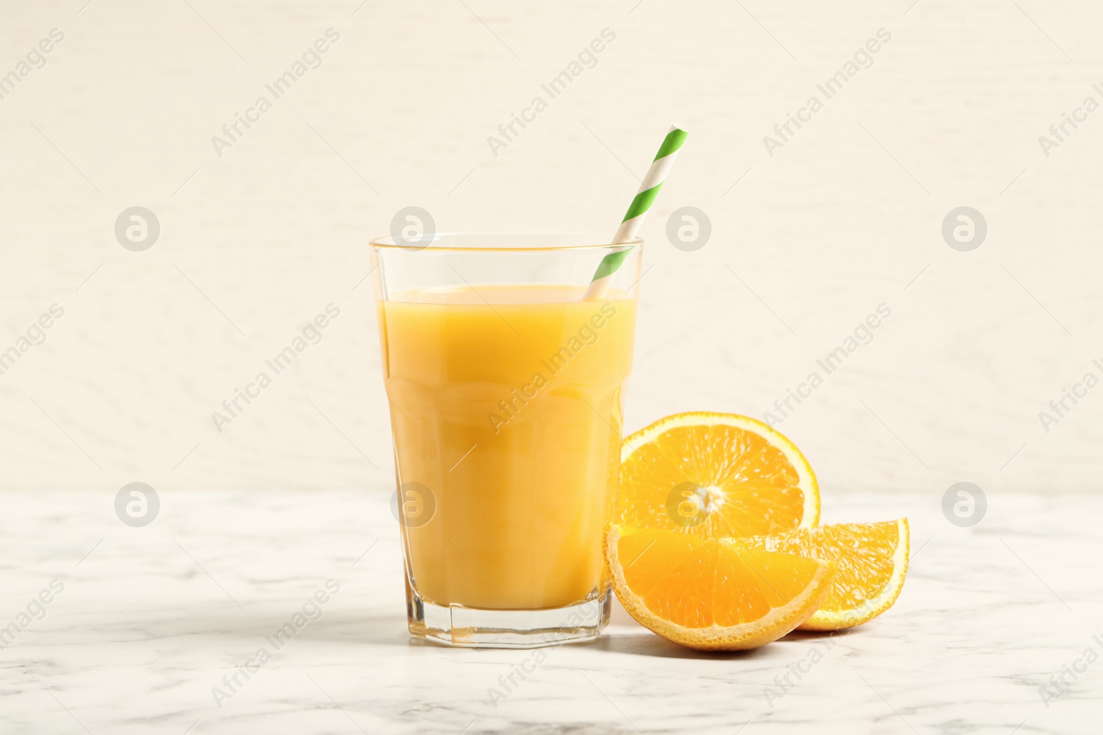 Photo of Glass of orange juice and fresh fruits on white marble table