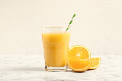 Photo of Glass of orange juice and fresh fruits on white marble table