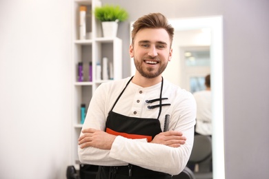 Photo of Professional male hairdresser with comb and scissors in salon