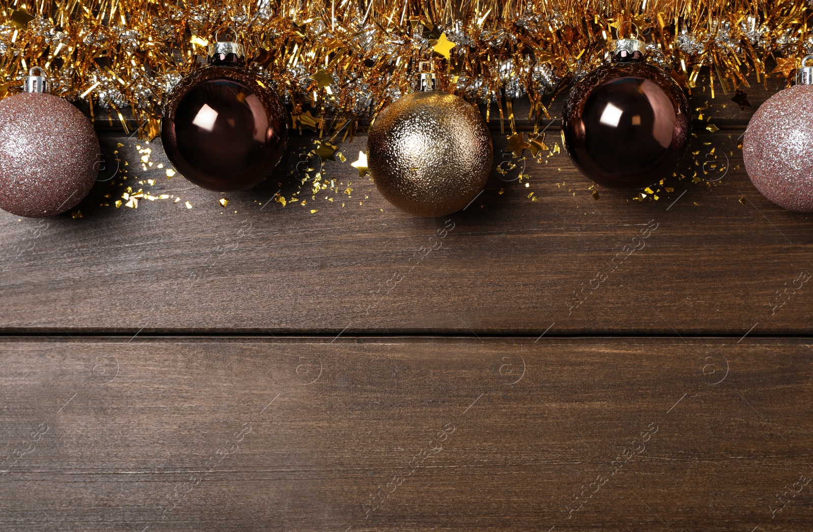 Photo of Bright tinsel and Christmas balls on wooden background, flat lay. Space for text