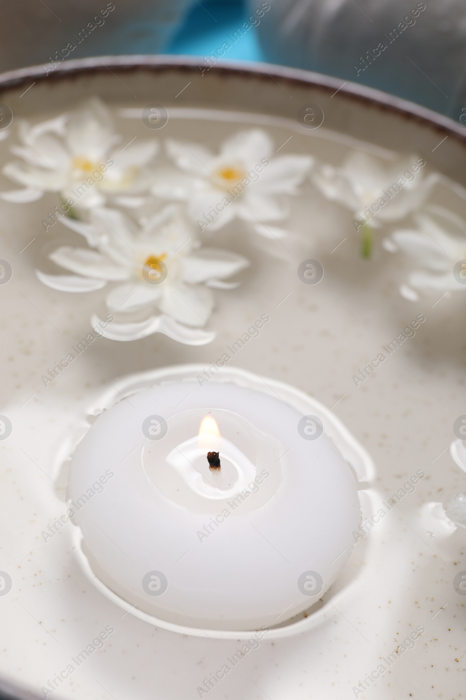 Photo of Spa composition with burning candle and beautiful flowers in water, closeup