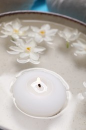 Photo of Spa composition with burning candle and beautiful flowers in water, closeup