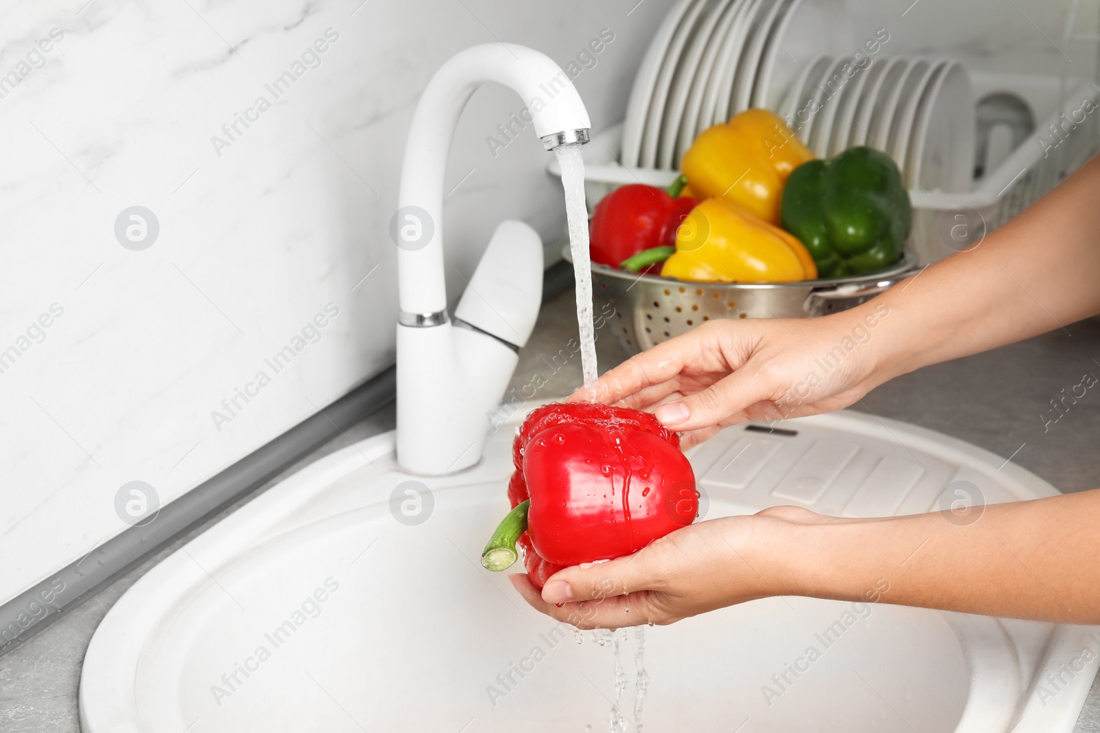 Photo of Woman washing paprika pepper in kitchen sink, closeup